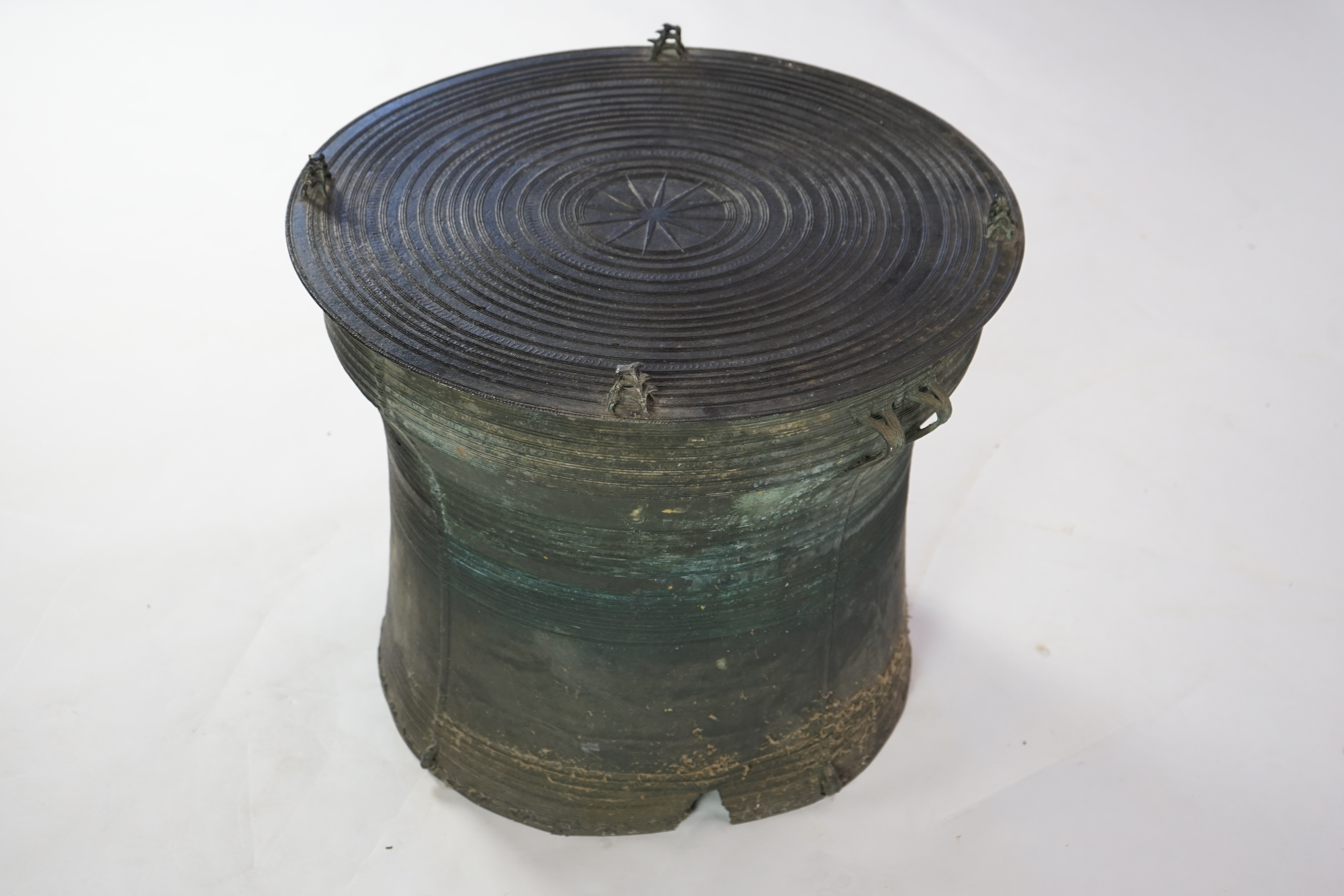 A Shan States bronze rain drum, the concentric ring decorated top mounted with stylised frogs, sides with loop handles and raised ring decoration, 66cm diameter, 57cm high